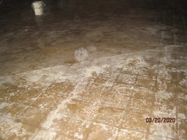 Photo of floor of home in a asbesotos remediation project managed by Precision Environmental Services. Lots of dust and debris visible on the floor.