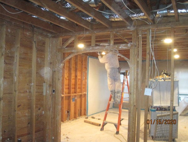 Photo from interior of house in a asbestos remediation project managed by Precision Environmental Services. All drywall and interior walls are removed exposedg house wiring is seen.