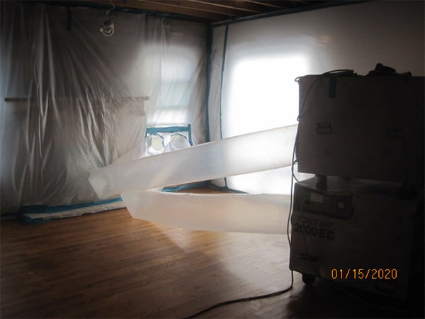 Photo of the interior of a home with equipment venting the air in an asbesotos removal project overseen by Precision Environmental Services.